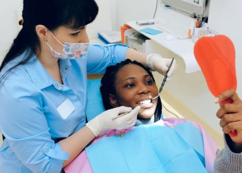 Dentista em consultório com paciente sorrindo.