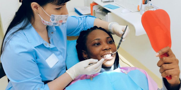 Dentista em consultório com paciente sorrindo.