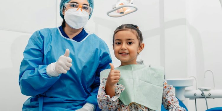 Dentista e criança feliz em consultório odontológico.