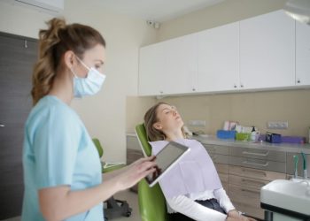 Dentista fazendo análise para indicar tratameto para a paciente que está na cadeira.