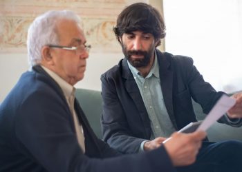 Corretor de seguros mostrando contrato para cliente idoso.