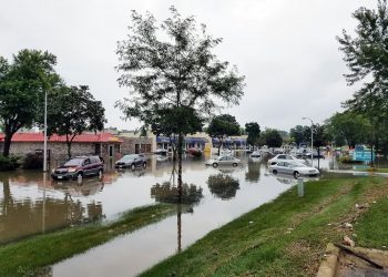 Bairro inundado de água após enchente com vários carros submersos.