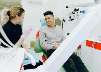 Dentista fazendo atendimento de homem em um consultório odontológico.