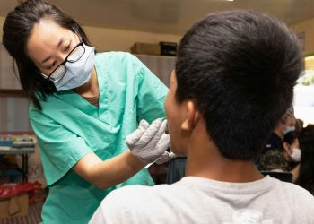 Dentista examinando boca de paciente.