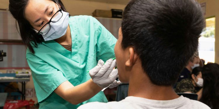Dentista examinando boca de paciente.